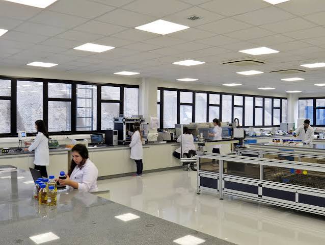 Laboratório com pesquisadores de jaleco branco trabalhando nas bancadas
