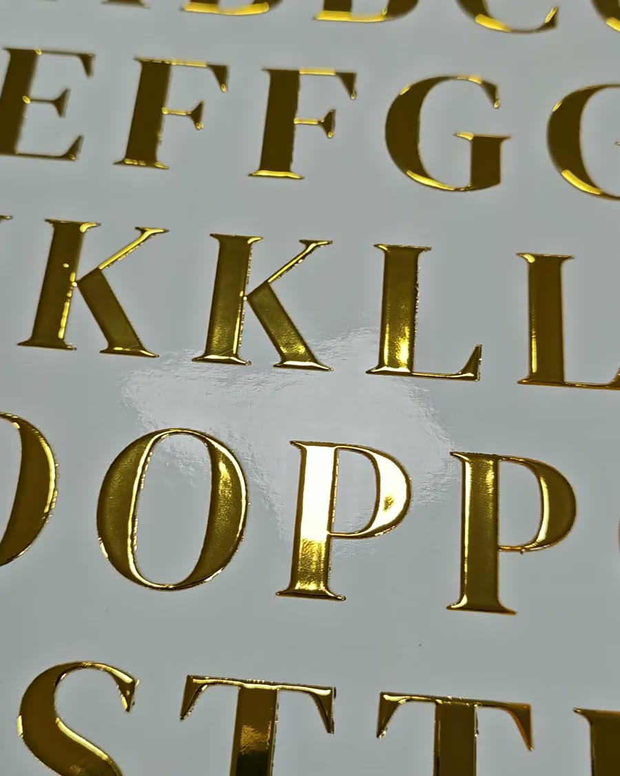 Letras do alfabeto em dourado espelhado sobre fundo branco