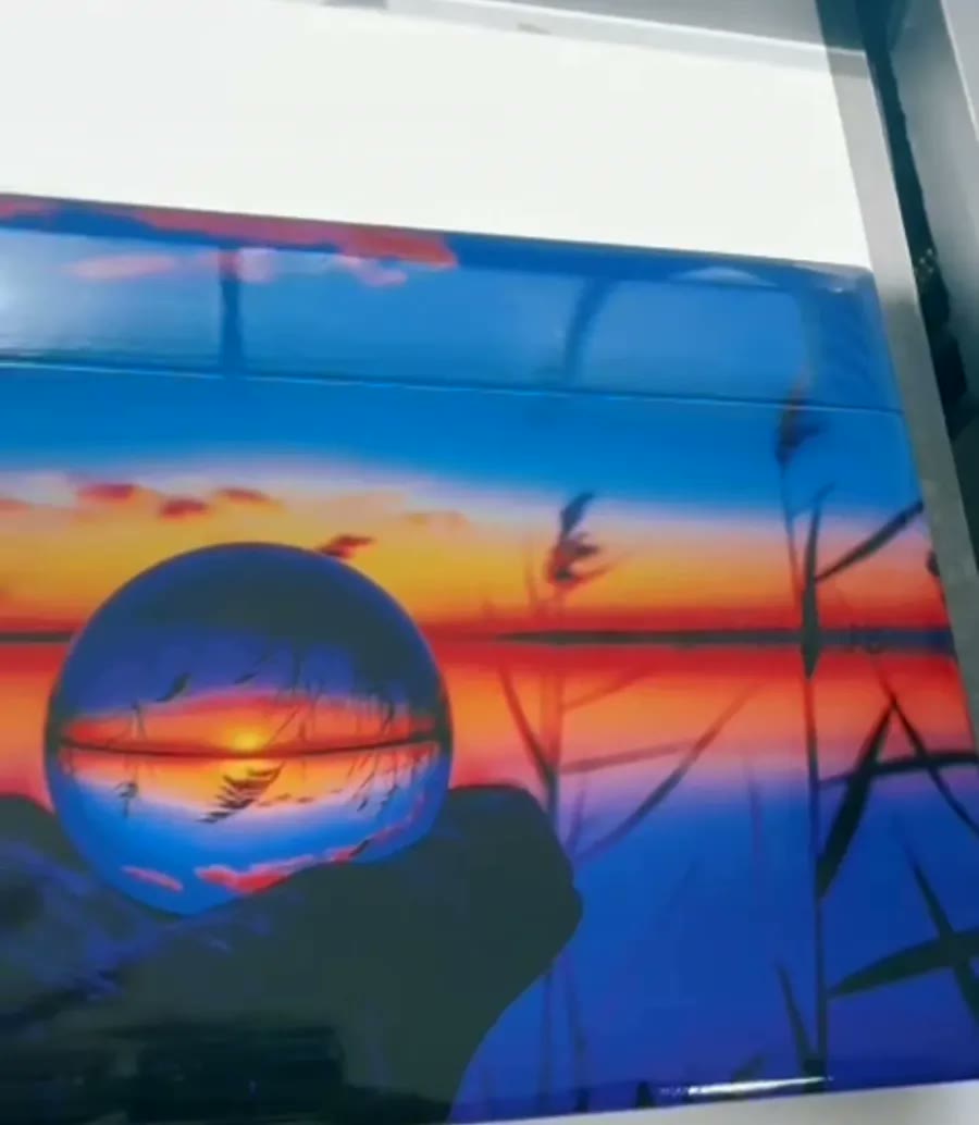 Placa com fotografia de pôr do sol refletido em uma esfera de vidro